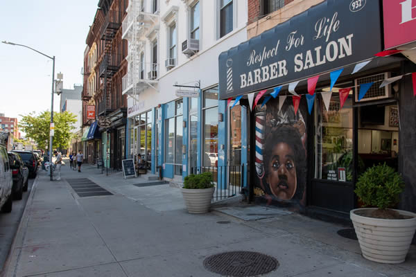 Sidewalk view of Respect for Life Barber Salon in foreground in Clinton Hill.