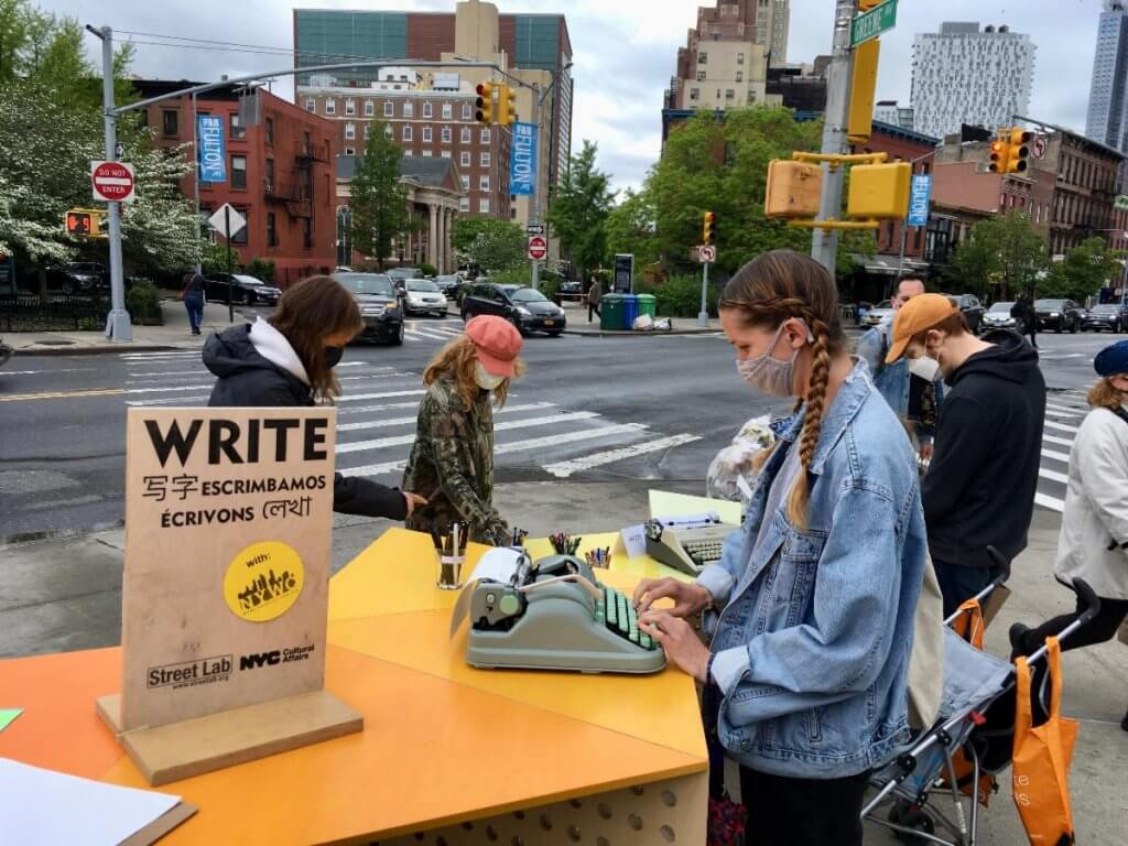 Woman using typewriter at Street Lab desk on Fulton Street
