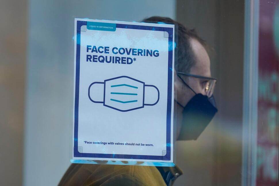 Face Covering signage in a window while a patron is in the background