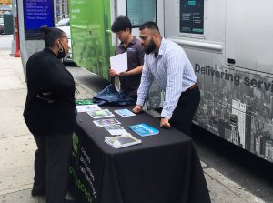 SBS reps talking to a visitor to their mobile unit table on Fulton St.