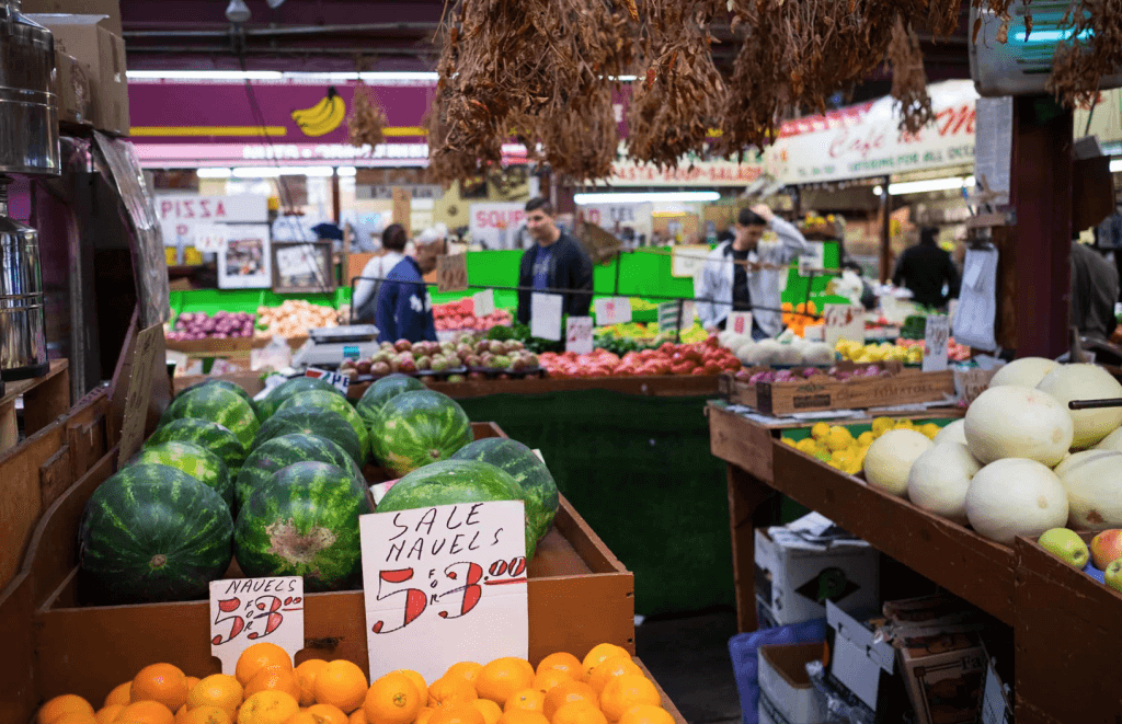 Produce section at a market showing prices and shoppers