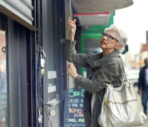 Female merchant pulling down storefront gates