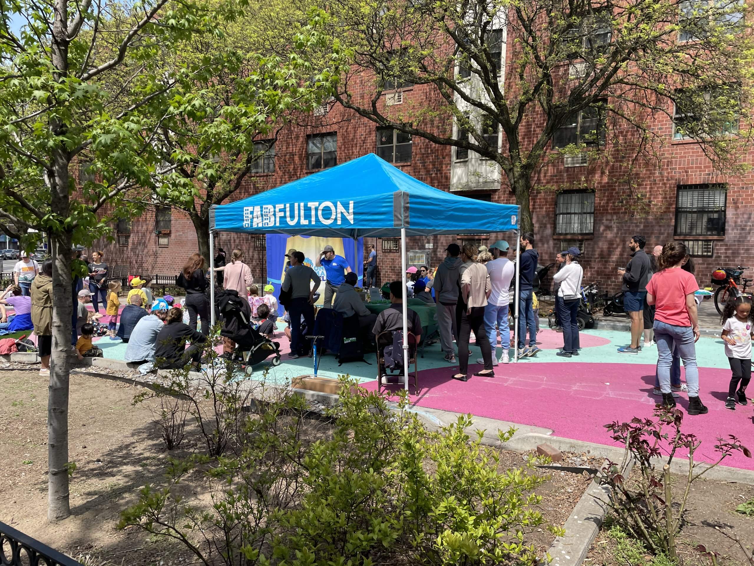Scene from a past FAB Fulton plaza event, showing the blue branded tent with people inside and around it enjoying the outdoor event