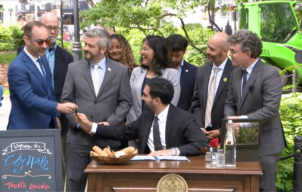 Scene from press conference with NYC mayor, councilmembers, et al, signing the new outdoor dining law